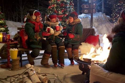Explore the magical wonders of Santa's Village in the North Pole with Mrs. Claus' photo of elves warm and cozy by the campfire.